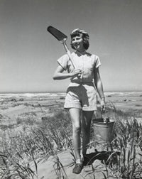 Young woman walking on Long Beach carrying sand pail and shovel poster print.