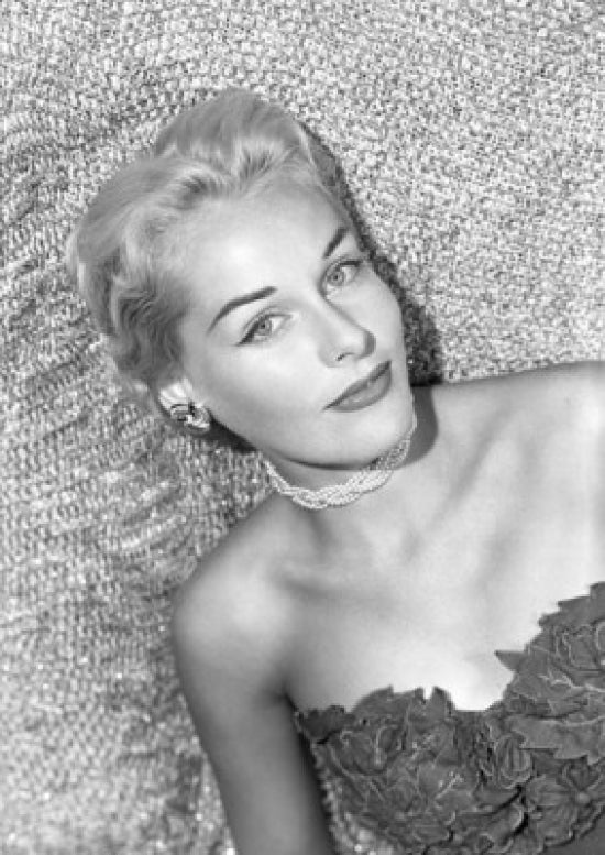 Portrait of a young woman lying on bed in a studio shot.