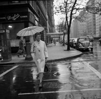 Young woman with umbrella crossing street in rain poster print.