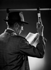 Man standing and reading newspaper poster print, studio shot.
