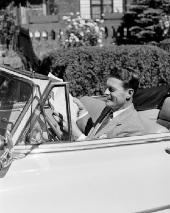 Man sitting in convertible car reading newspaper poster print