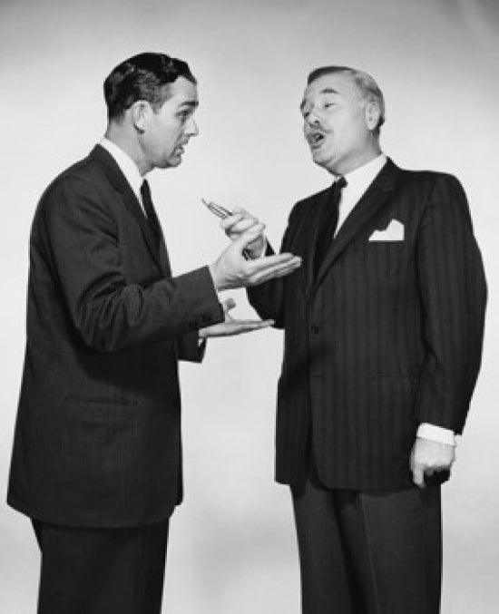 Poster print of two businessmen talking to each other in a professional setting.