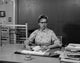 Teacher Sitting at Desk in Classroom Poster Print