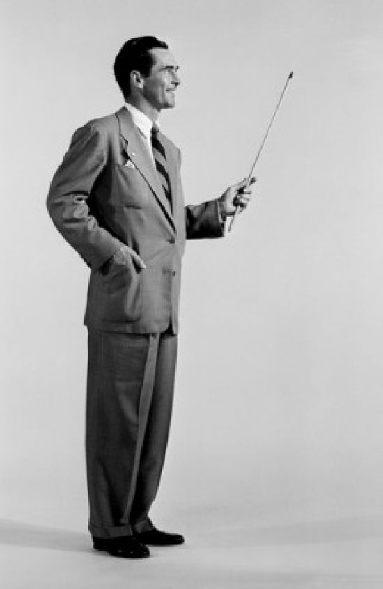 Studio shot of a man holding a baton in a creative setting.