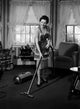 Young Woman with Vacuum Cleaner Poster Print showcasing modern domesticity.