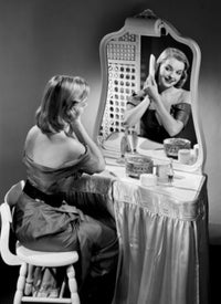 Portrait of a beautiful woman combing hair in front of a mirror poster print.