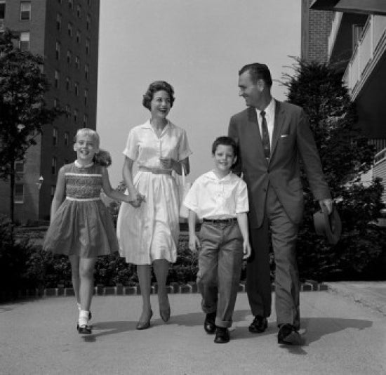 Boy and girl walking with parents outside flats poster print.