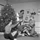 Family opening Christmas gifts around a Christmas tree poster print.