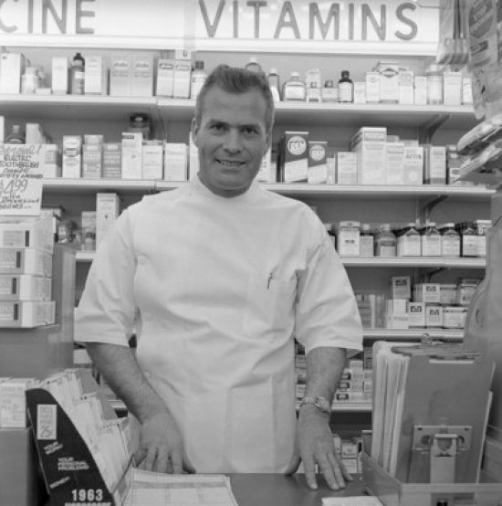 Portrait of Pharmacist in Drug Store Poster Print showcasing vintage pharmacy scene.