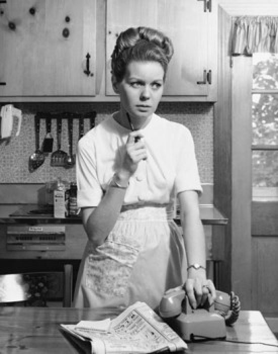 Young woman standing in kitchen holding phone poster print.