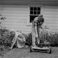Senior couple mowing grass in backyard poster print.
