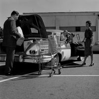 Parents and kids loading shopping bags into car trunk poster print