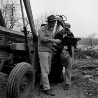 Two men standing by tractor discussing plans poster print