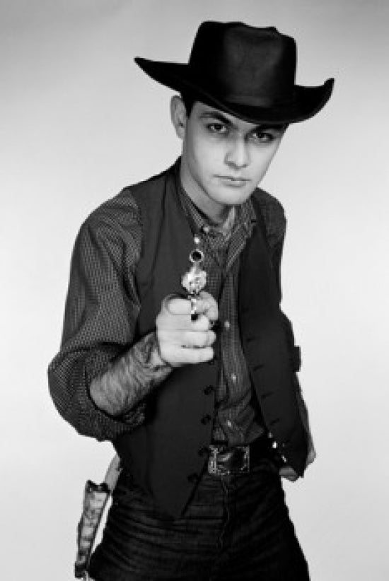 Studio portrait of cowboy aiming gun at camera poster print.
