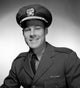 Studio portrait of a smiling male pilot in uniform.
