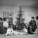 Family with two children opening gifts near a Christmas tree poster print