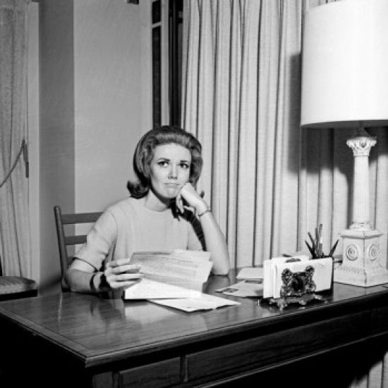 Sad young woman sitting at desk holding a letter poster print.