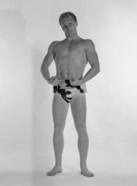 Poster print of a muscular man wearing animal print trunks in a studio shot.