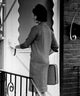 Young woman standing in front of entrance door using doorbell poster print.