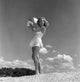 Young woman in swimsuit standing on the beach with a beach ball poster print.