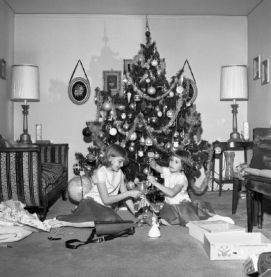 Two Girls Preparing Christmas Tree Poster Print showing festive holiday decor.