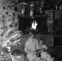 Children reading a book under a Christmas tree poster print.