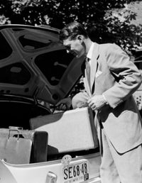 Poster print of a man placing a suitcase in a car trunk, symbolizing adventure.
