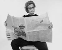 Mid adult woman reading a financial newspaper with an expressive face.