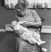 Grandmother Feeding Baby Poster Print showcasing a tender moment of love.