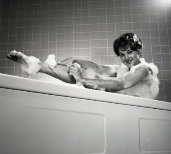 Portrait of young woman washing leg in bath - Poster Print