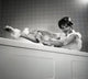 Portrait of young woman washing leg in bath - Poster Print