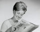 Close-up of a young woman reading a newspaper poster print.