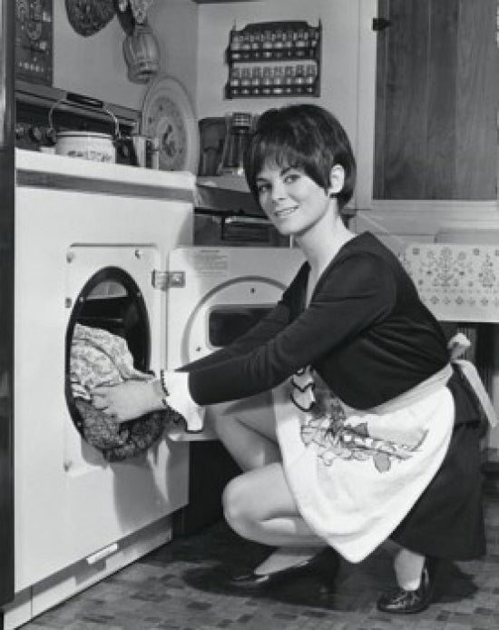 Portrait of a young woman putting clothes into a dryer poster print.