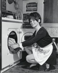 Portrait of a young woman putting clothes into a dryer poster print.