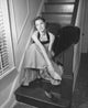High angle view of a young woman sitting on a staircase holding her ankle poster print.