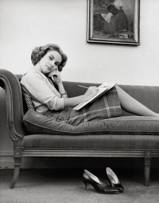 Portrait of a young woman sitting on a chaise longue poster print.