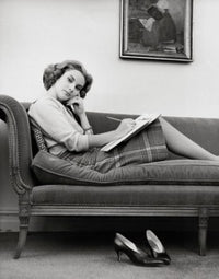 Portrait of a young woman sitting on a chaise longue poster print.