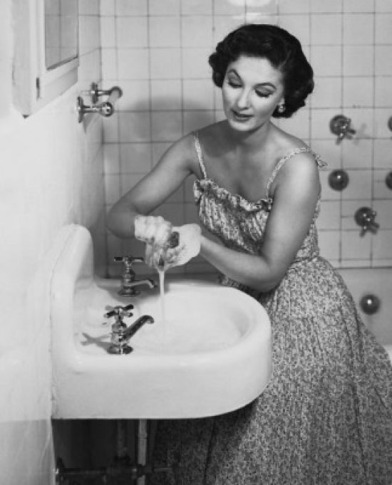 Poster print of a young woman washing her hands in the bathroom sink.