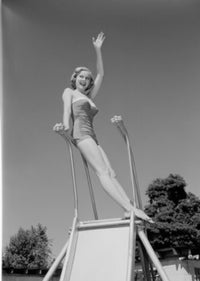 Young woman in swimwear sliding down a water slide poster print.