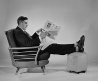 Poster print of a man sitting in an armchair reading a newspaper.