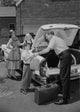 Parents with children loading suitcases into a car poster print