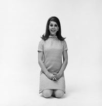 Portrait of a young woman kneeling on the floor and smiling, poster print.