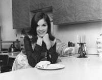 Portrait of a young woman leaning against a kitchen counter, poster print