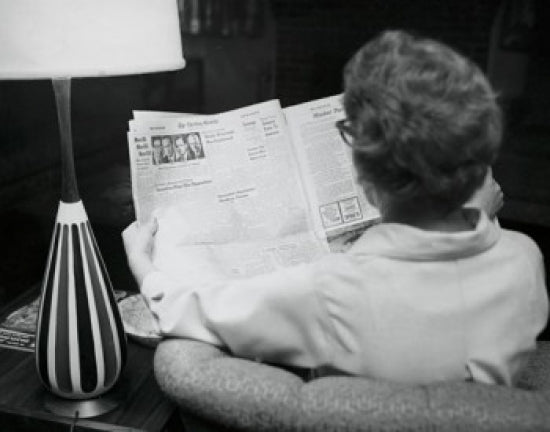 Poster print featuring the rear view of a young woman reading a newspaper.