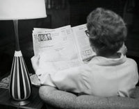 Poster print featuring the rear view of a young woman reading a newspaper.