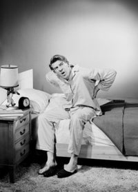 Mid adult man wearing pajamas sitting on bed poster print.