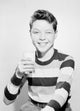 Studio portrait of a boy holding a glass of milk, joyful childhood moment.
