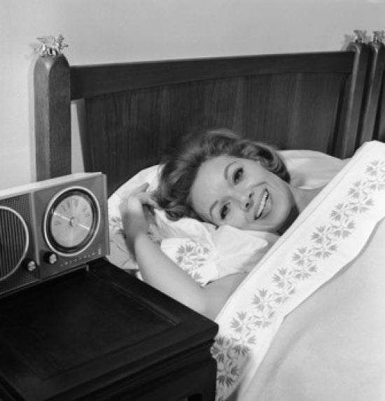 Young woman lying in bed smiling poster print