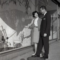 Mid adult couple admiring a window display poster print.