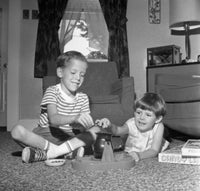 Poster print of two boys playing with a toy game on the living room floor.